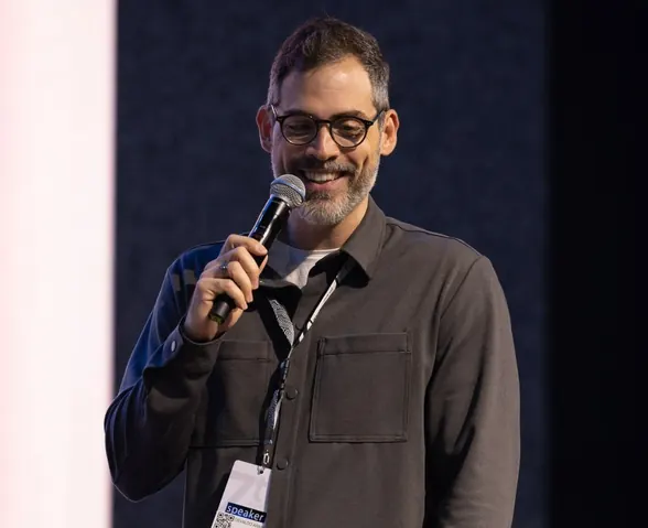 Osvaldo Aranha sorrindo no palco, com o crachá de palestrante
